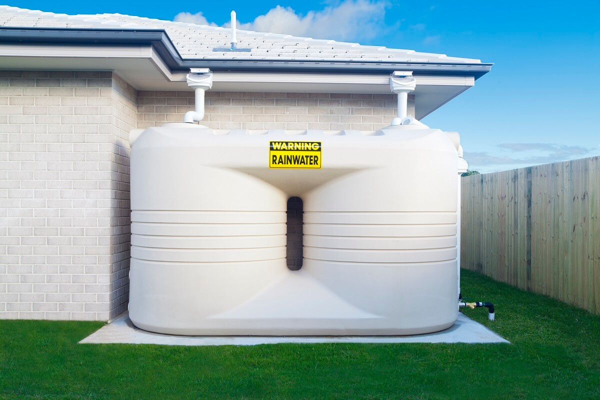 Rainwater tank in backyard, properly fitted by professional plumber in North Sydney.
